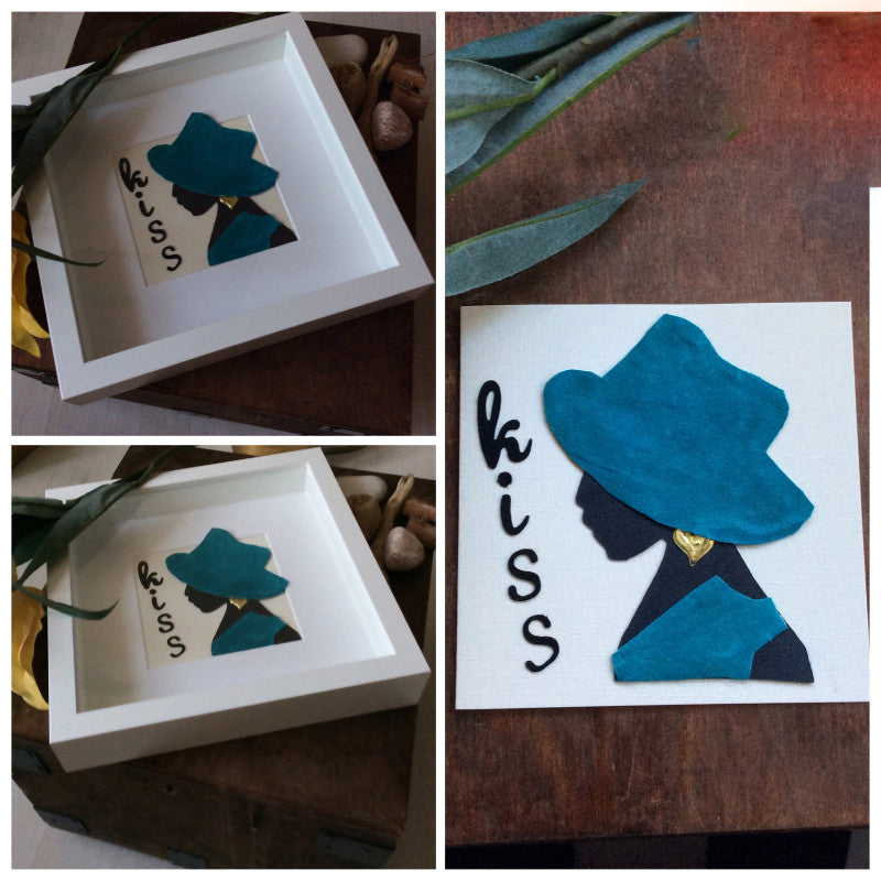 Handmade greeting card.  Black card silhouette of a lady wearing a turquoise hat and tunic and gold earring. Wording on the card is Kiss